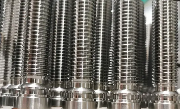 Pièces métalliques filetées alignées en série dans un atelier industriel